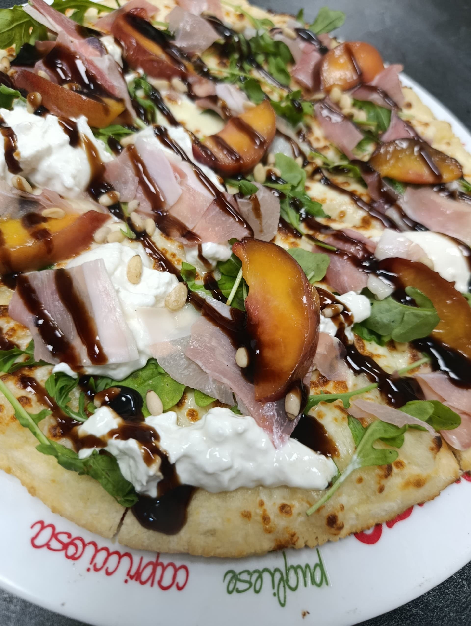 Pizza Dolce Vita : burrata, jambon cru, pêche rôtie, pignons et crème balsamique