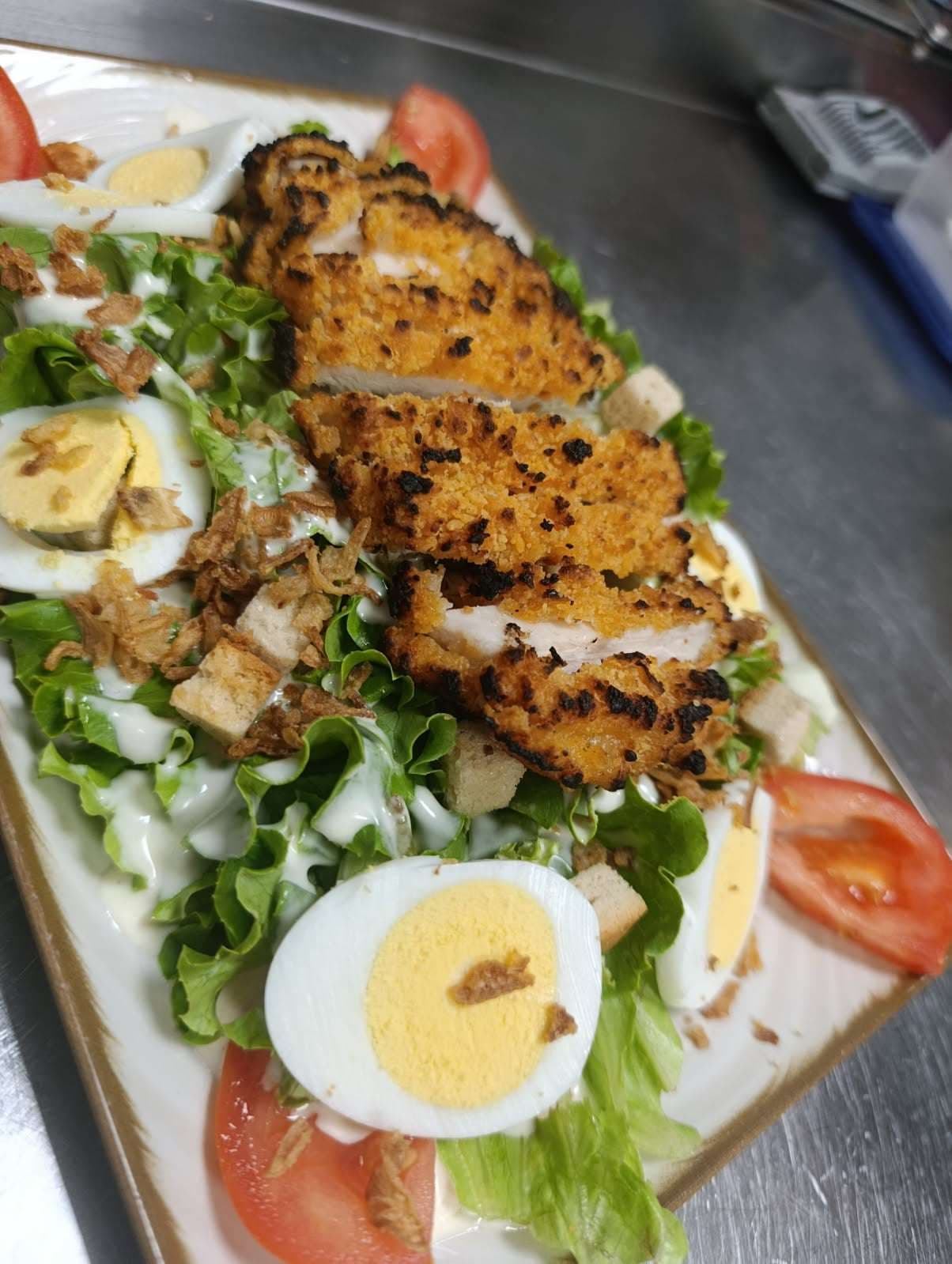 Salade César : salade, oignons et poulet frits, croûtons, tomate et œuf dur